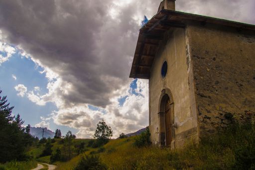 Rustic stone building under dramatic cloudy sky in a rural landscape.