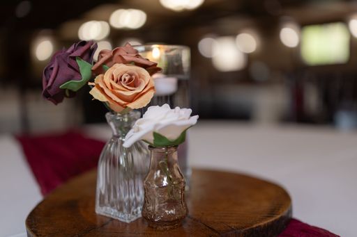A close-up of elegant floral centerpieces in glass vases on a wooden stand.