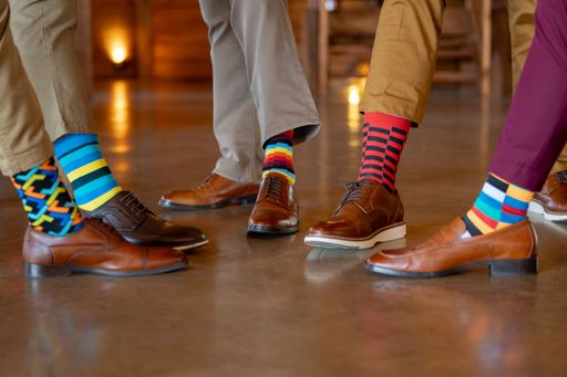 A close-up of men's colorful socks and brown leather shoes on a polished floor, showcasing fashion and style.