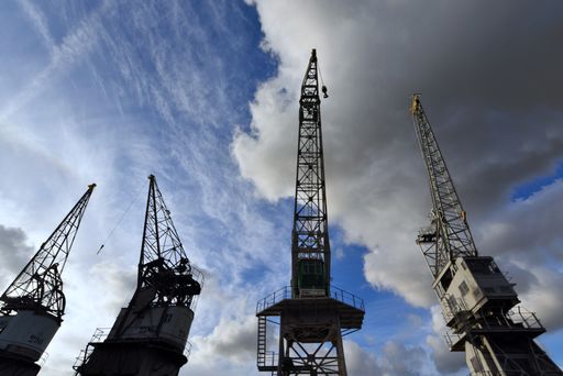 A low angle shot of construction cranes under a cloudy sky - port of Antwerp
