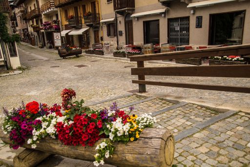 Charming European street with colorful flowers and rustic buildings, showcasing cobblestone paths and inviting outdoor cafes.