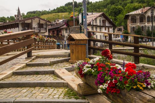 Charming street view in a European village with colorful flowers and rustic buildings, showcasing a quaint atmosphere.