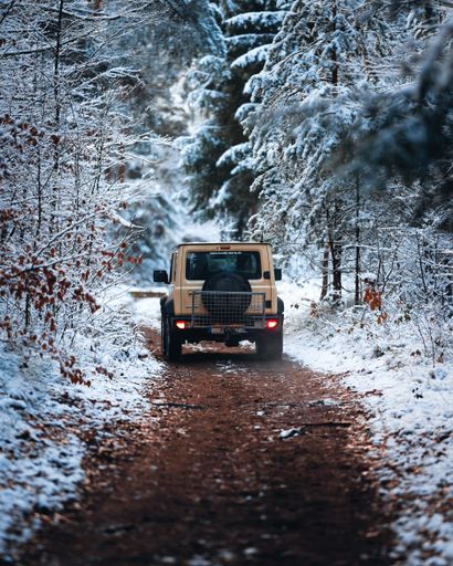 A vertical shot of a car in a snowy forest