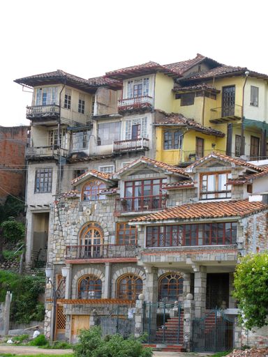 Layered colonial-style houses with stone facades and wooden balconies in the historic center of Cuenca.