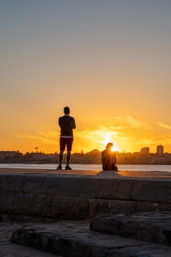 A beautiful Sunset at the Pier of Tamariz Beach, in Estoril, Portugal and two people contemplating