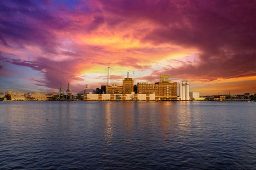 The Domino Sugar factory along the Baltimore Riverfront on the Patapsco River at sunset in Baltimore Maryland USA