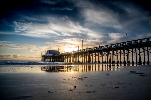 A landscape view of a wooden fishing pier and a building on it at sunset.