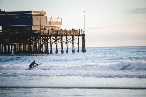 A Surfer hitting the waves at Newport Beach in California, USA at sunset
