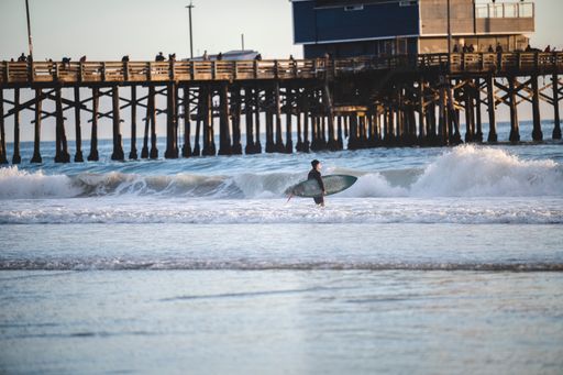 A rear view of a surfer with a surfboard preparing to catch the wave  at Newport Beach, California