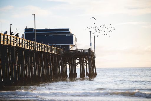 A group of people standing on the old wooden dock at Newport Beach in California