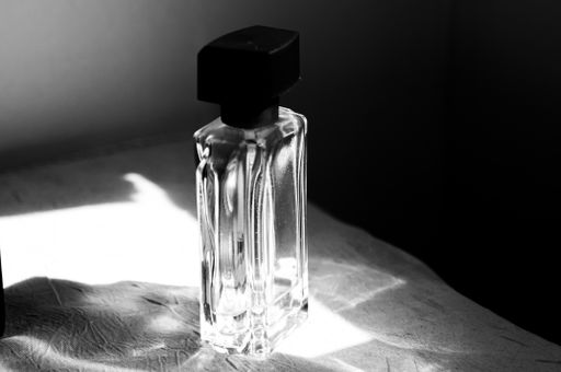 A grayscale shot of a perfume bottle on the table