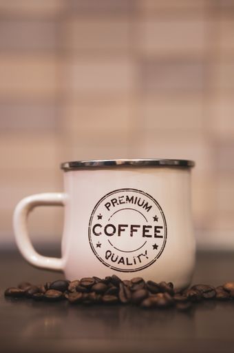 A closeup of a coffee mug with text PREMIUM COFFEE QUALITY next to coffee beans in Poznan, Poland
