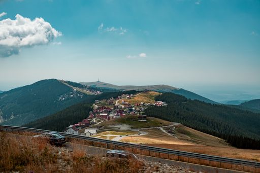 A high angle shot of a village on the hills near a highway under the beautiful blue sky