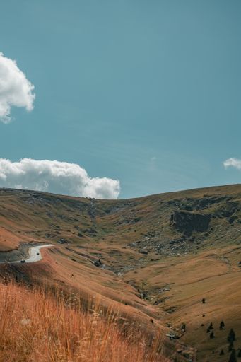 A vertical low angle shot of a road on a hill under the beautiful blue sky
