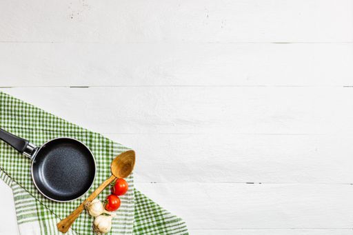 The Cherry tomatoes, garlic, pan, and wooden spoon on the table