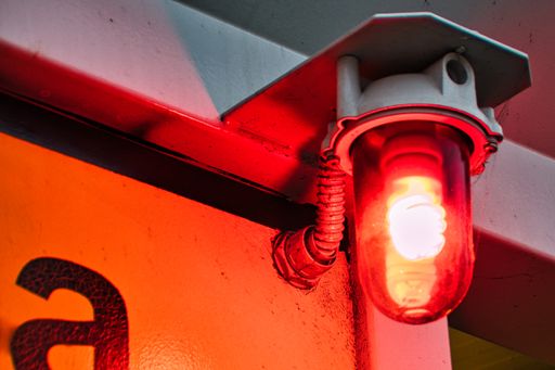 A closeup of a red warning light bulb on the wall