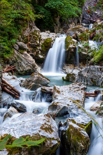 A vertical shot of waterfalls flowing through rocks and trees