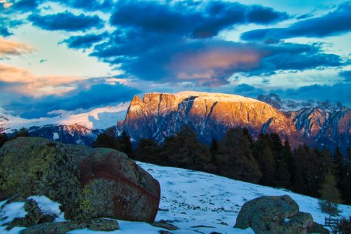 A high angle of mountain Schlern, Italy covered with snow under the sunlight surrounded with rocks and forests