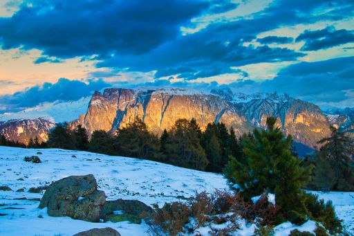 A panoramic of mountain Schlern, the Alps from a high hill covered with snow and forests under the sunlight