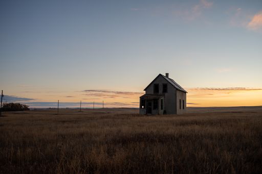 A view of an old wooden house in the middle of the field