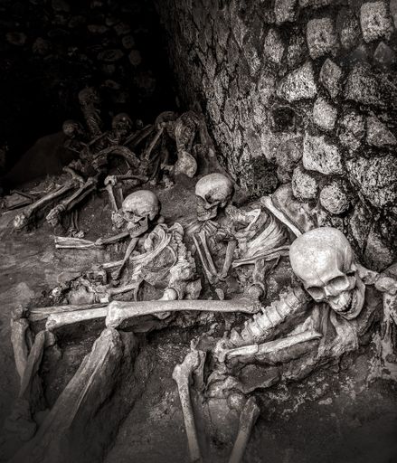 A vertical grayscale shot of the human skeletons in the cave.