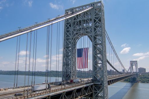 A bright morning at the George Washington Bridge in Fort, USA with the US flag hanging from it