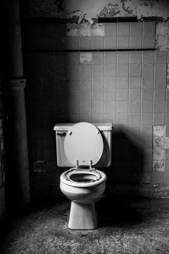 A vertical shot of a scary toilet in black and white in prison