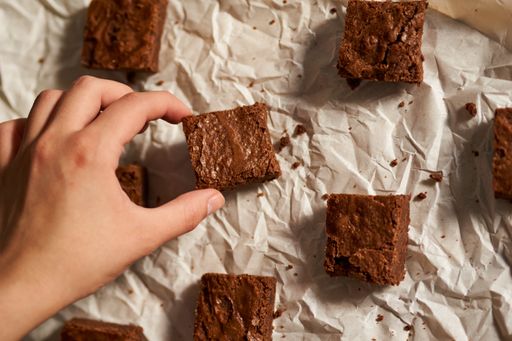 A hand putting the piece of chocolate sponge cake on the white napkin