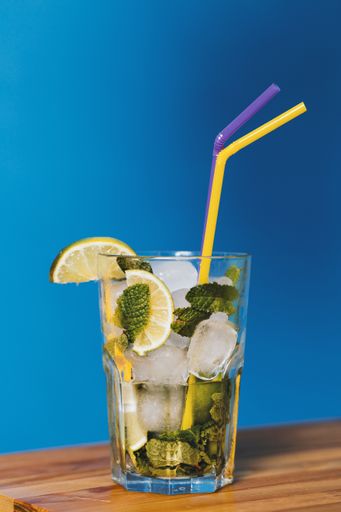 A vertical closeup shot of lime cocktail in a drinking glass with two straws