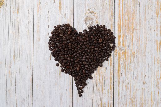 A top view of heart-shaped coffee beans on a wooden desk