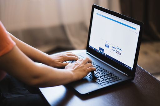 A selective closeup shot of a person typing on a black laptop