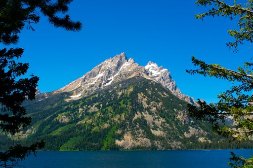 A landscape of Lake Jenny surrounded by rocky hills under the sunlight in Wyoming, the US