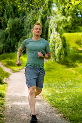 A young Caucasian man running in a park in sportswear during the day in Arhus City