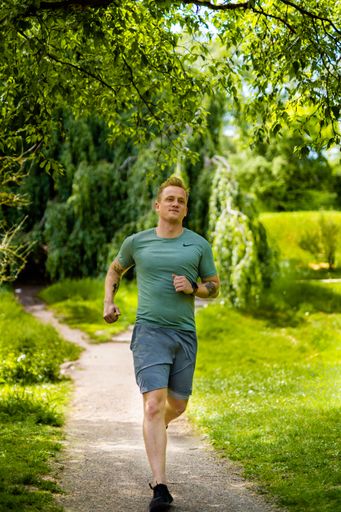 A young Caucasian man running in a park in sportswear during the day in Arhus City