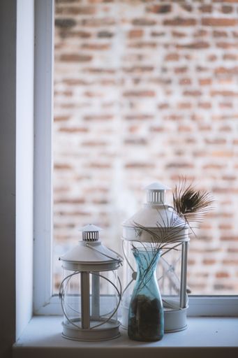 A vertical selective closeup shot of large and medium glass lantern lamps on a windowsill