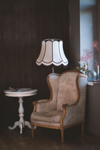 A vertical shot of a brown armchair near a white round table and a lamp