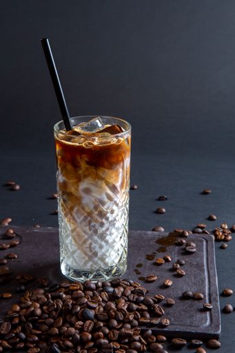A vertical shot of an iced latte coffee glass on a wooden table in the restaurant