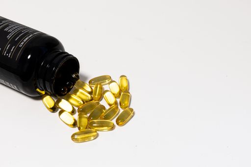 Close up one bottle of yellow Omega 3 vitamins and essential fish oils gel cap pills isolated on white background, low angle side view