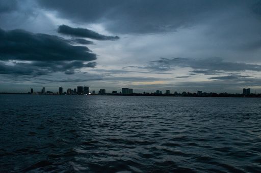 Phnom Penh dusk sunset, as seen from the Mekong and Tonle Sap rivers, with emerging sky scrapers. Monsoon season and rain clouds approaching the city