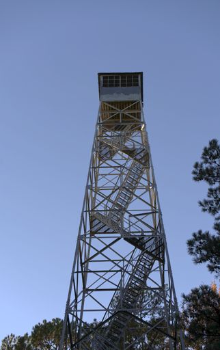 A low angle shot of a forest fire observation tower under the blue sk