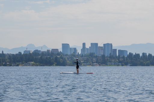 A man paddleboarding in Lake Washington with the background of Bellevue, Seattle, USA