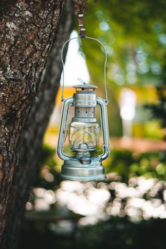 A vertical shot of an oil lamp hanging on a tree