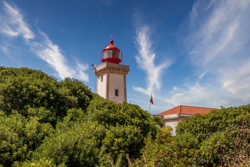 A historical lighthouse surrounded by trees at Praia do Carvoeiro in Algarve, Portugal