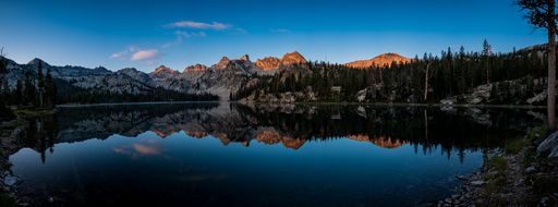 A panoramic view of the reflection of the Sawtooth Mountains in the  Alice Lake