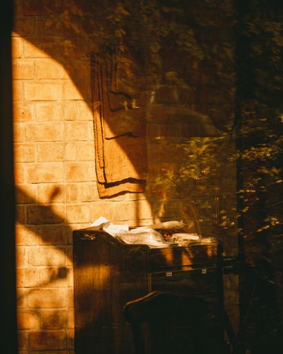 A vertical shot of the sun shining through a window near a writing desk
