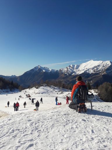 Many people skiing in the snowy mountains in Italy under a blue sky on a sunny winter day