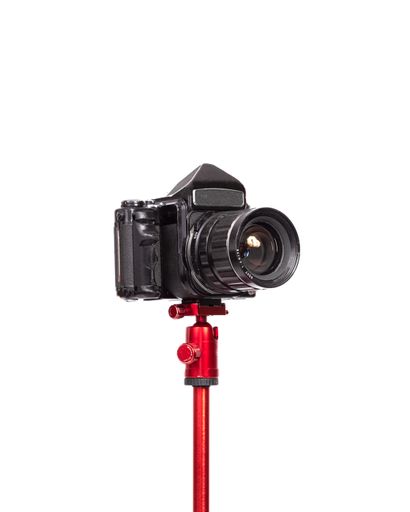 A closeup of a professional camera on a red tripod on a white background