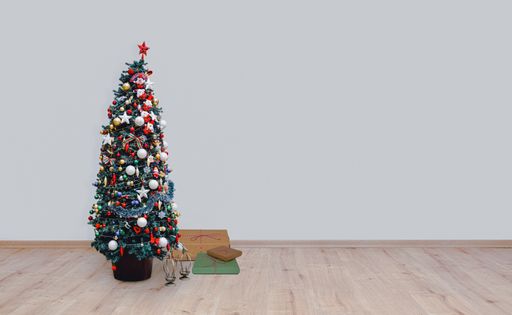 A decorated christmas tree on hardwood floor in a empty room
