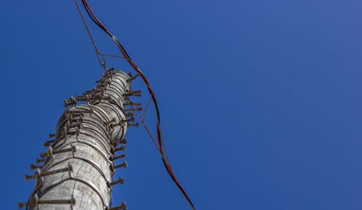 A low angle shot of a wooden pole for electricity against a clear sky