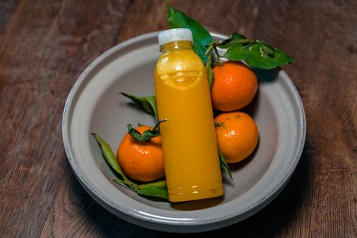 A closeup shot of orange juice and tangerines in the bowl on a wooden table